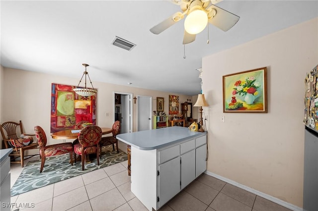kitchen with a peninsula, light tile patterned floors, light countertops, and hanging light fixtures