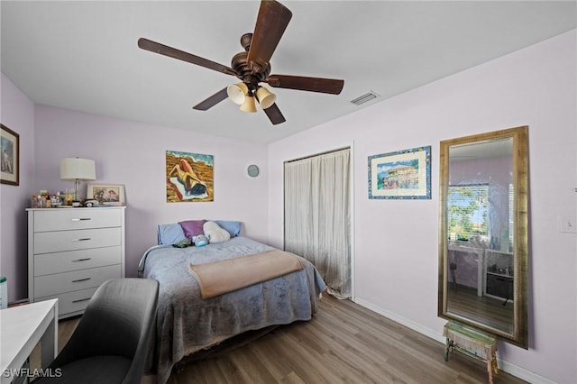 bedroom with wood finished floors, baseboards, ceiling fan, and a closet