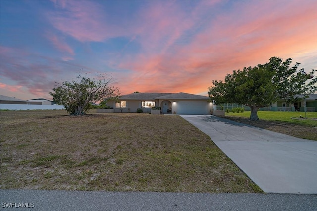 ranch-style home featuring concrete driveway, an attached garage, and a front lawn