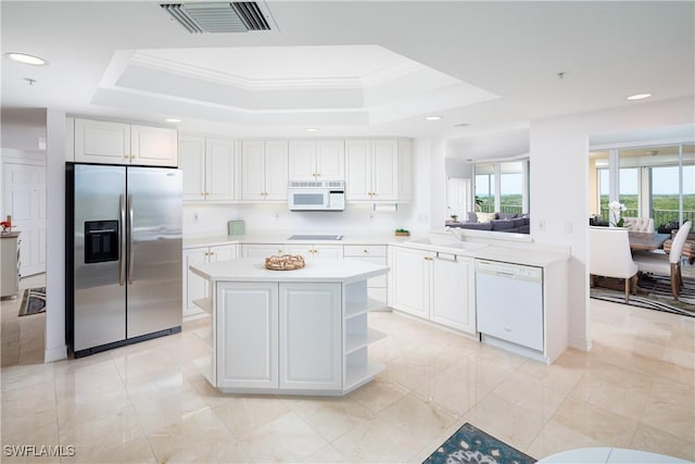 kitchen with a sink, white appliances, visible vents, light countertops, and a raised ceiling