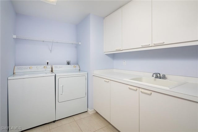 washroom with washing machine and dryer, cabinet space, light tile patterned flooring, and a sink
