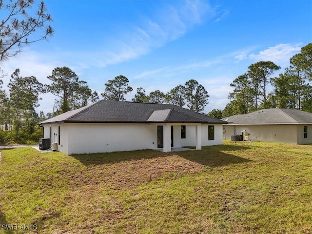 631 Summit Ave S, Lehigh Acres, FL 33974 - back of house featuring central air condition unit, a yard, and stucco siding