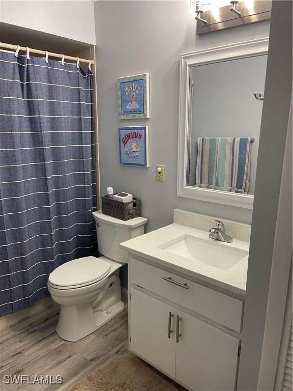 bathroom featuring toilet, a shower with curtain, wood finished floors, and vanity