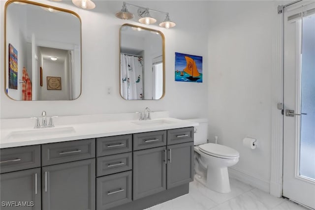 full bath with double vanity, toilet, and a sink