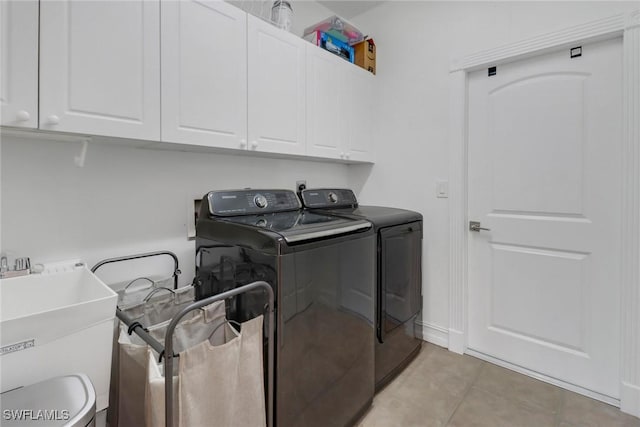 washroom featuring a sink, cabinet space, light tile patterned floors, and washing machine and dryer