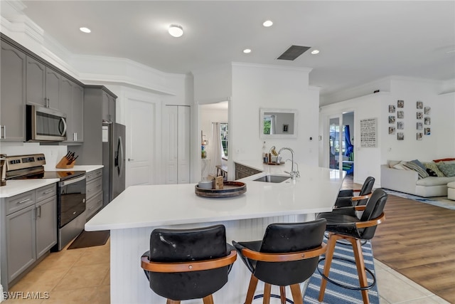 kitchen featuring gray cabinets, a sink, light tile patterned floors, ornamental molding, and stainless steel appliances
