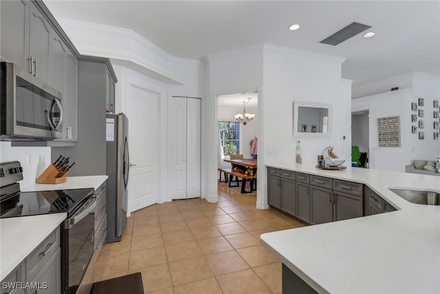kitchen with gray cabinets, a sink, appliances with stainless steel finishes, light tile patterned floors, and a notable chandelier