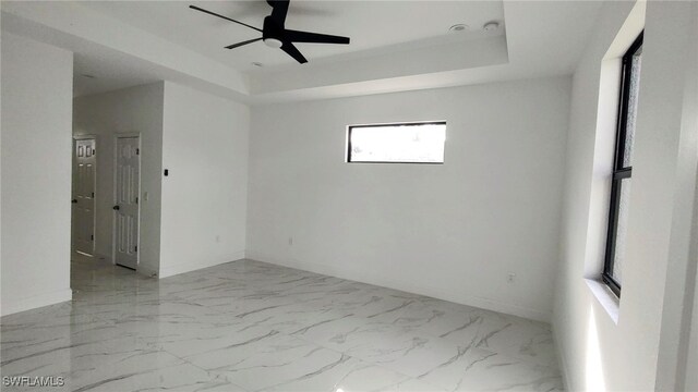 208 Genoa Ave S, Lehigh Acres, FL 33974 - spare room featuring a raised ceiling, baseboards, a ceiling fan, and marble finish floor
