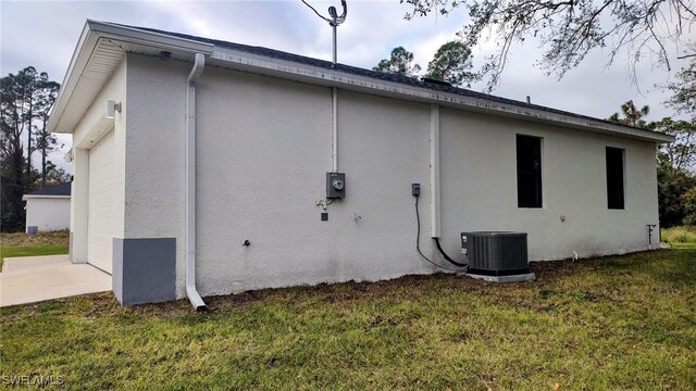 208 Genoa Ave S, Lehigh Acres, FL 33974 - view of property exterior featuring stucco siding, central AC, and a yard
