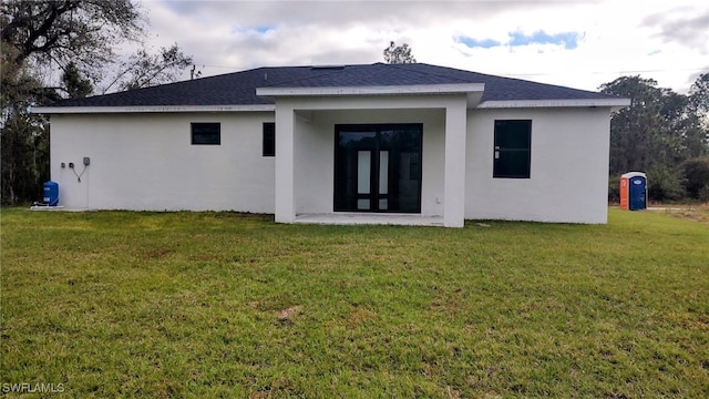 208 Genoa Ave S, Lehigh Acres, FL 33974 - rear view of house featuring a shingled roof, stucco siding, and a yard