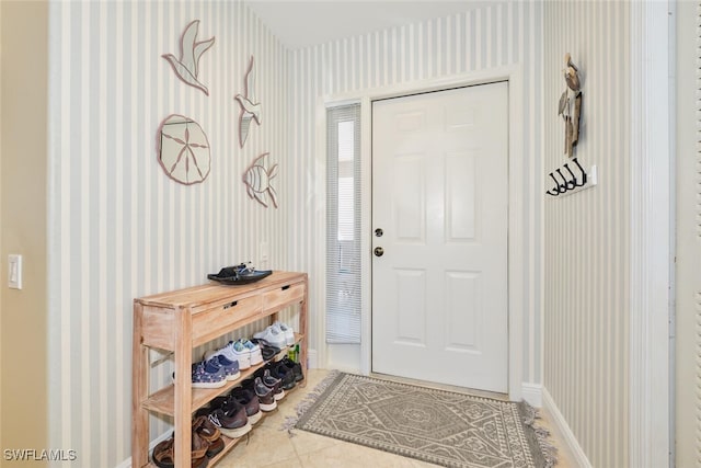 entrance foyer featuring baseboards, tile patterned floors, and wallpapered walls