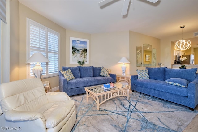 living area with visible vents, wood finished floors, baseboards, arched walkways, and ceiling fan with notable chandelier