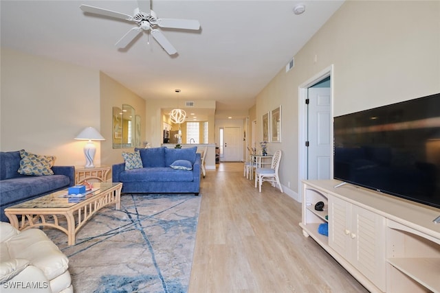 living area featuring visible vents, a ceiling fan, light wood finished floors, and baseboards