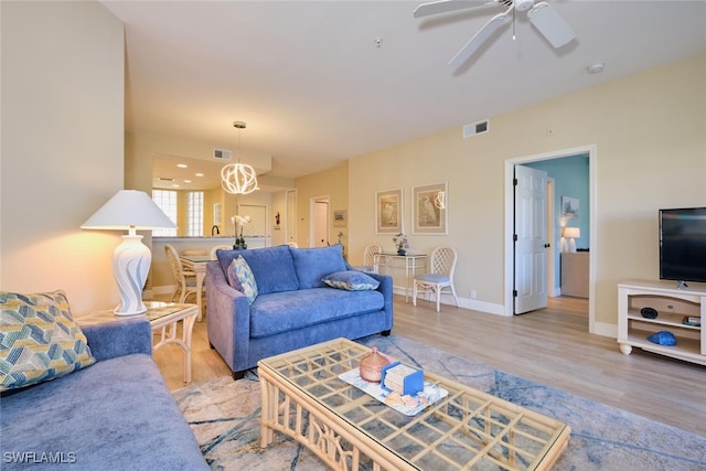 living room with baseboards, ceiling fan, visible vents, and wood finished floors