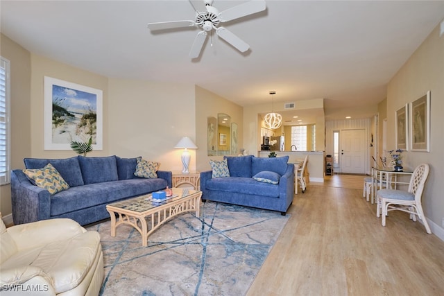 living area featuring visible vents, light wood-style flooring, ceiling fan, and baseboards