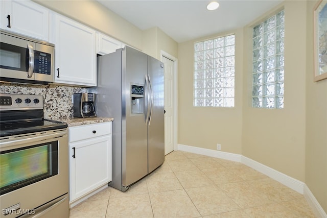 kitchen with backsplash, stainless steel appliances, baseboards, and white cabinetry