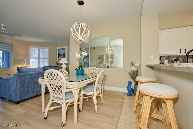 dining room featuring baseboards, ceiling fan with notable chandelier, and light wood-style flooring