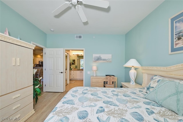 bedroom with ceiling fan, visible vents, wood finished floors, and ensuite bath
