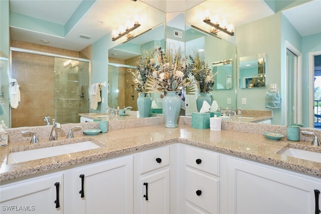bathroom featuring double vanity, a sink, a stall shower, and visible vents