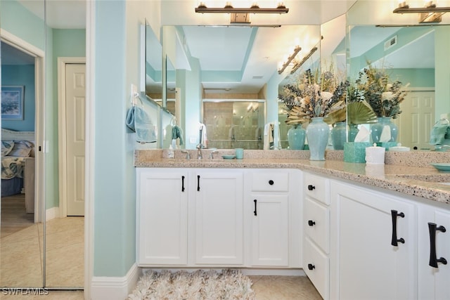 full bathroom with double vanity, a shower stall, a sink, and tile patterned flooring