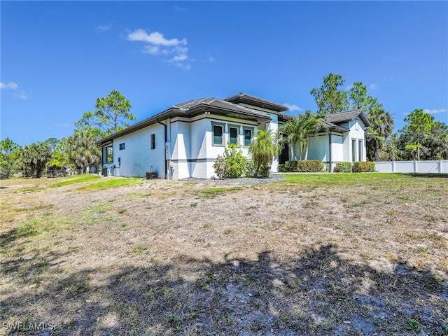 rear view of property featuring fence and stucco siding