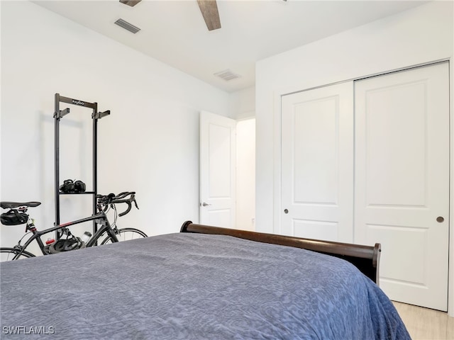 bedroom with a ceiling fan, visible vents, light wood finished floors, and a closet