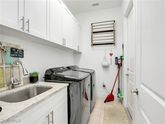 laundry room featuring cabinet space, a sink, baseboards, light tile patterned flooring, and washer and clothes dryer
