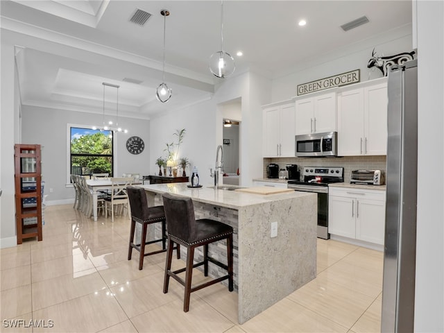 kitchen with visible vents, crown molding, a sink, backsplash, and stainless steel appliances