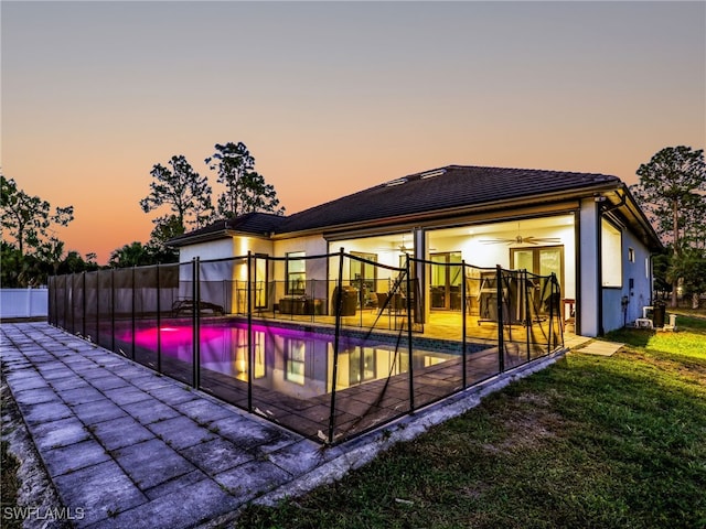 back of property featuring ceiling fan, a patio area, fence, a fenced in pool, and a yard