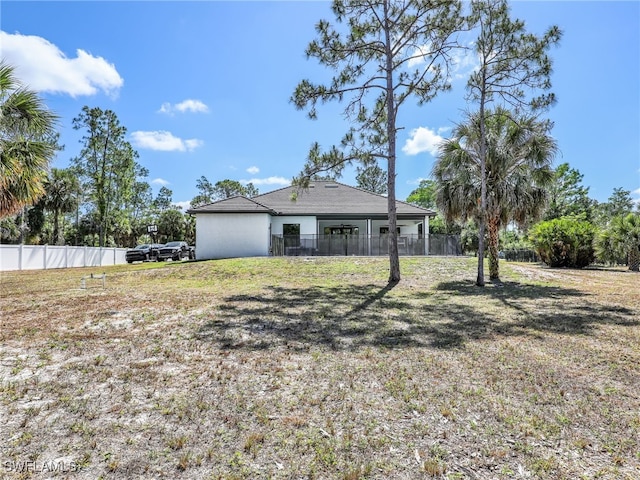 rear view of property with a lawn and fence