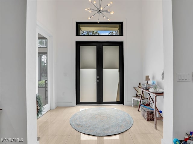 tiled foyer with an inviting chandelier and french doors