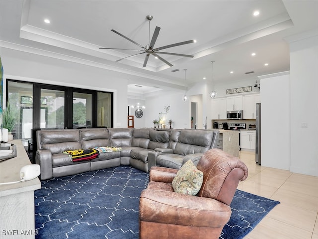 living area featuring a raised ceiling, ceiling fan with notable chandelier, and recessed lighting