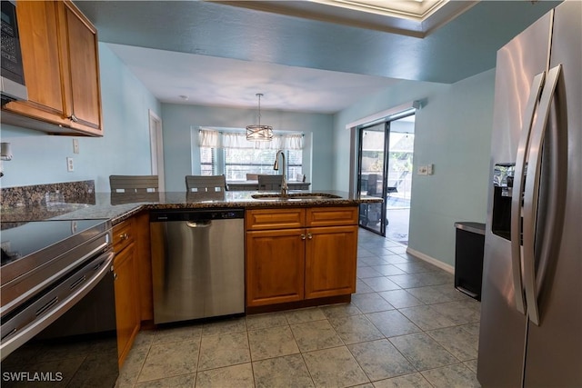 1209 SW 36th Ter, Cape Coral, FL 33914 - kitchen with appliances with stainless steel finishes, a sink, brown cabinetry, a peninsula, and pendant lighting