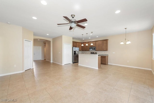 unfurnished living room with recessed lighting, arched walkways, baseboards, and ceiling fan with notable chandelier