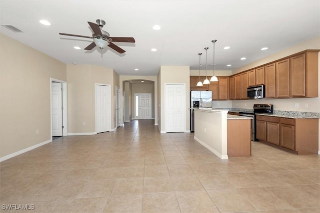 kitchen featuring visible vents, appliances with stainless steel finishes, arched walkways, brown cabinets, and open floor plan
