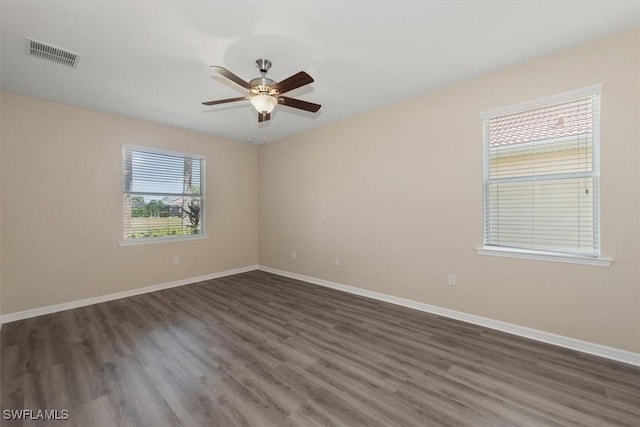 spare room with dark wood-style flooring, baseboards, and visible vents