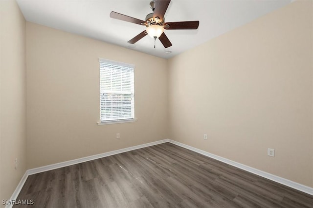 spare room featuring baseboards, dark wood finished floors, and ceiling fan