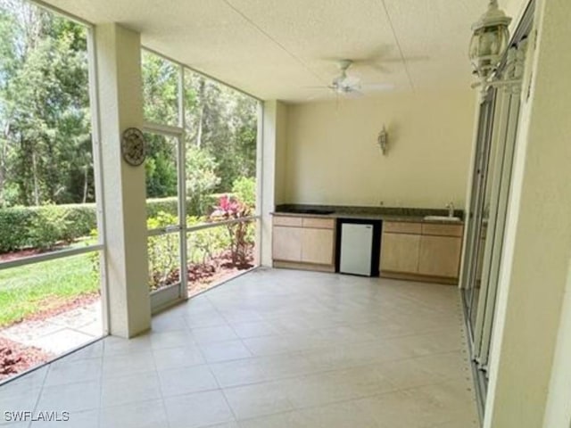 unfurnished sunroom with a ceiling fan, a wealth of natural light, and a sink