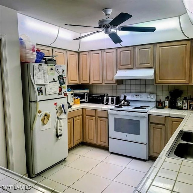 kitchen with white appliances, tile countertops, and under cabinet range hood