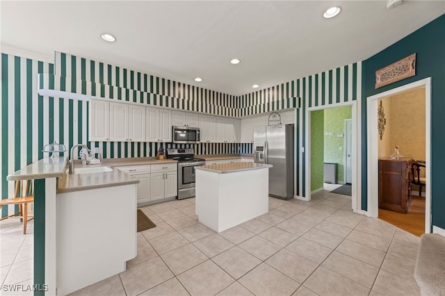 12541 Allendale Cir, Fort Myers, FL 33912 - kitchen featuring a sink, a peninsula, white cabinetry, wallpapered walls, and appliances with stainless steel finishes