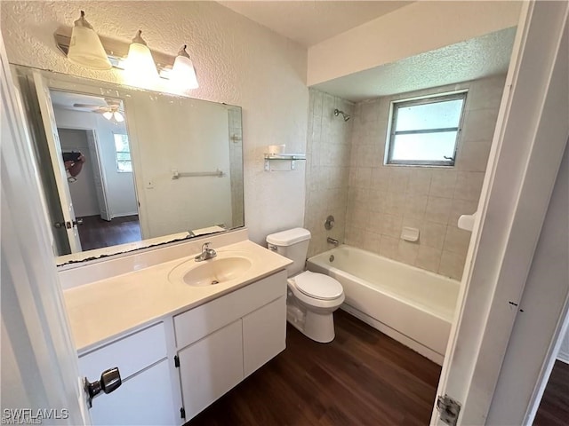bathroom featuring vanity, a textured wall, wood finished floors, toilet, and  shower combination