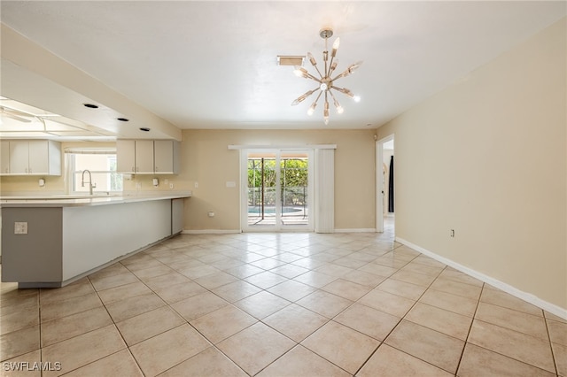 interior space featuring visible vents, light tile patterned flooring, baseboards, a chandelier, and a sink