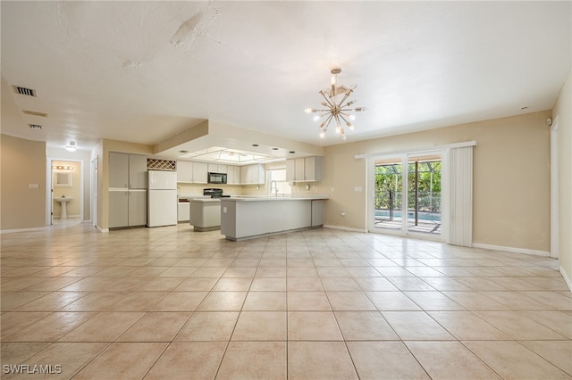 unfurnished living room featuring an inviting chandelier, visible vents, baseboards, a sink, and light tile patterned floors