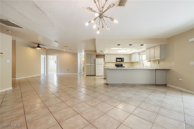 kitchen with a sink, light countertops, freestanding refrigerator, open floor plan, and visible vents