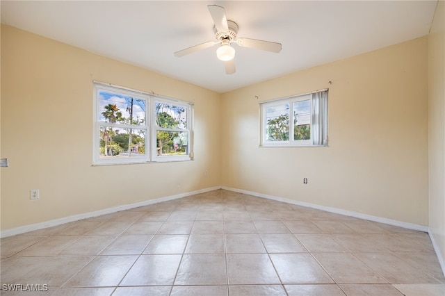 empty room with plenty of natural light, a ceiling fan, baseboards, and light tile patterned floors