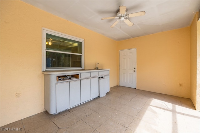 interior space with a ceiling fan, light tile patterned flooring, and a sink