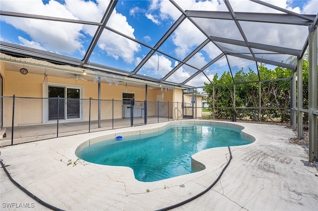 pool with a patio, ceiling fan, and glass enclosure