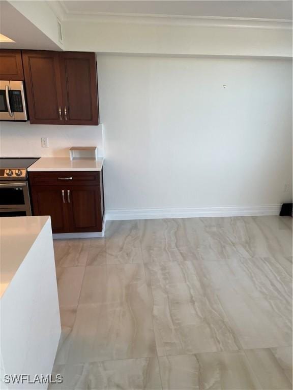 kitchen featuring appliances with stainless steel finishes, light countertops, baseboards, and light marble finish floors