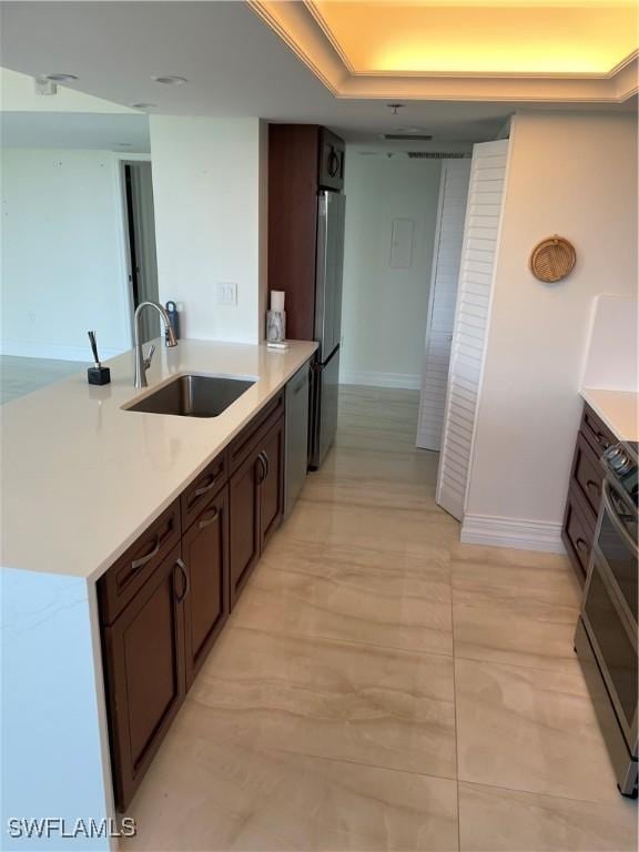 kitchen featuring freestanding refrigerator, a sink, dishwashing machine, light countertops, and range