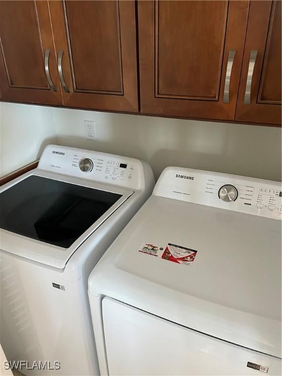 clothes washing area with washer and dryer and cabinet space